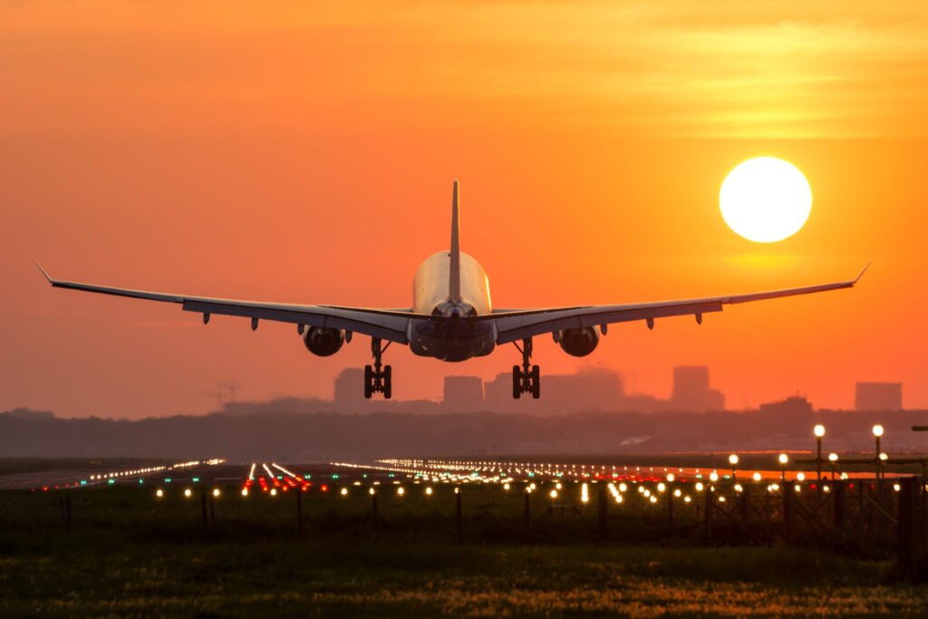 Airplane lands on airport strip at sunset