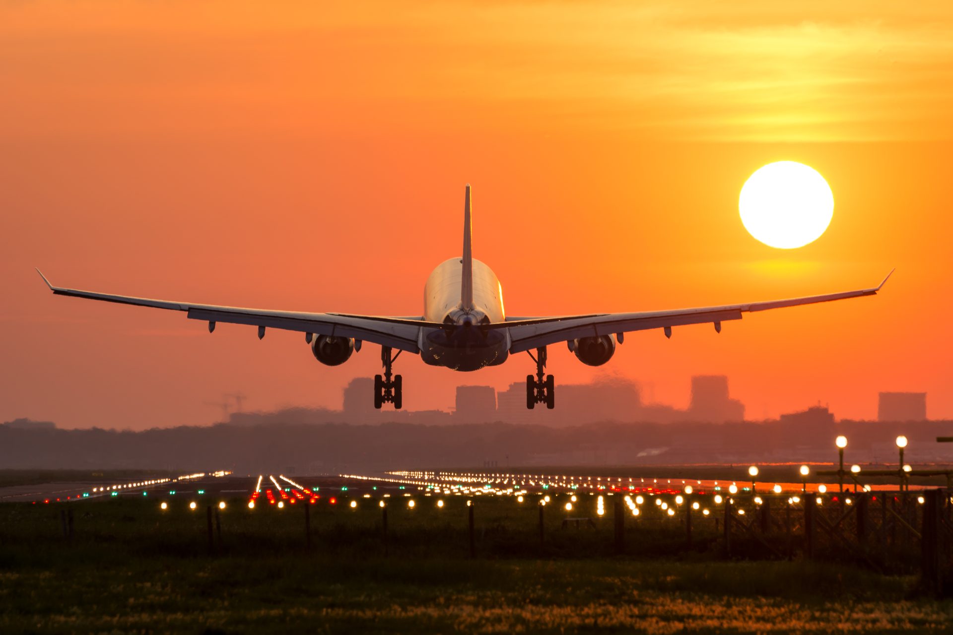 Airplane lands on airport strip at sunset