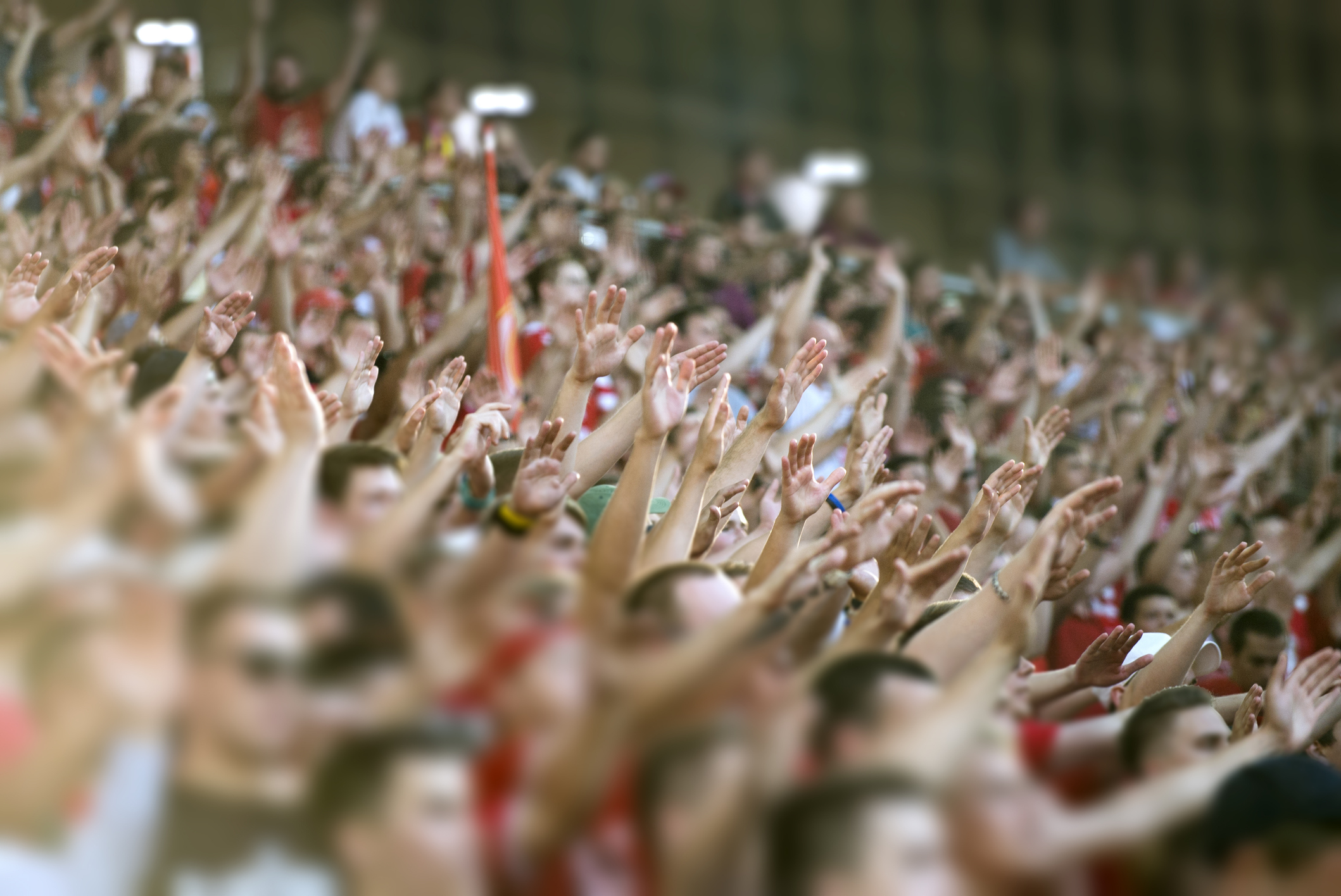 Sports fans in packed stadium with hands in the air